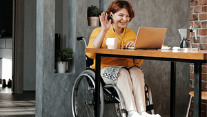 photo of woman in wheelchair speaking on the laptop and waving hello