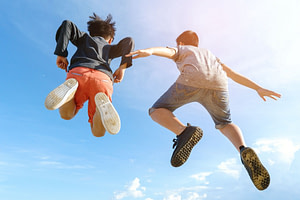 Two kids jumping in the air, photo taken from the ground